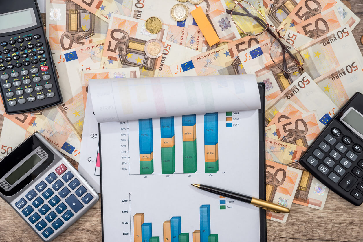 Image illustrant la gestion financière d'une SCI familiale pour revenus locatifs : des billets d'euros, une calculatrice, et un document affichant graphiques et statistiques symbolisent les aspects financiers et fiscaux de ce type de structure. Idéal pour optimiser les revenus locatifs en choisissant le régime fiscal adapté.