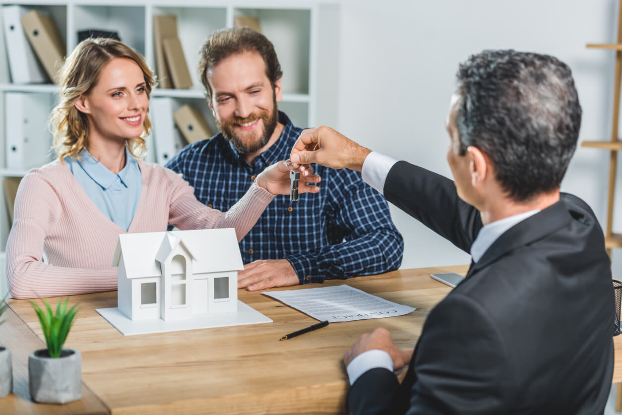 Un couple souriant reçoit les clés de leur nouvelle maison, acquise via une SCI, symbolisant une gestion patrimoniale optimisée et une sécurité renforcée pour leur avenir immobilier.