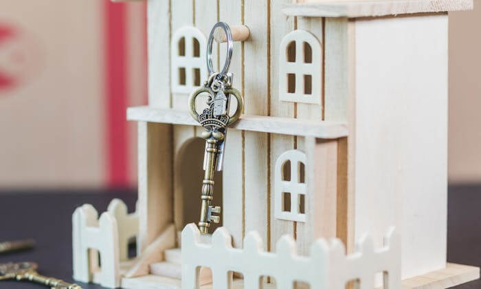 Une maquette de maison accompagnée d'une clé symbolise l'acte d'investir dans l'immobilier locatif.