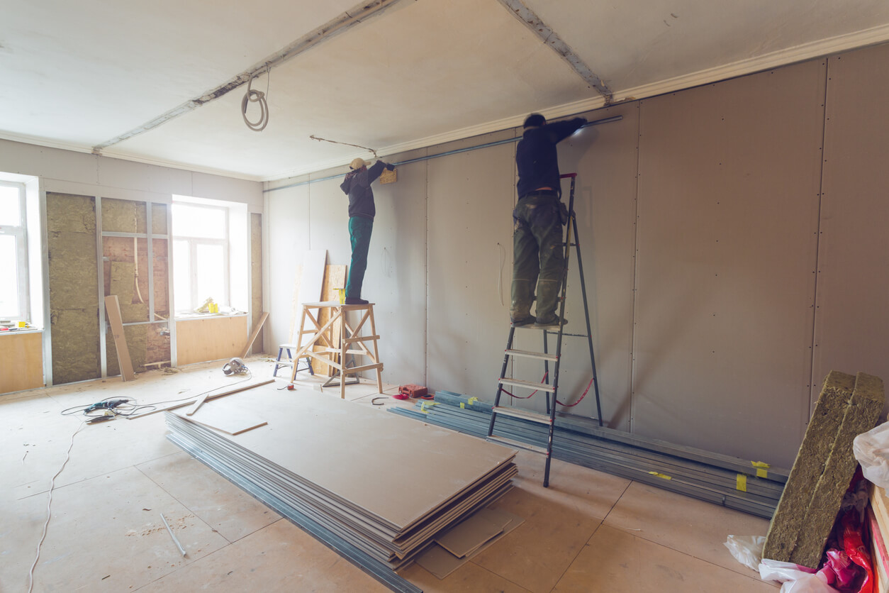 Des ouvriers sont en train d'installer des plaques de plâtre pour créer de nouveaux murs dans un appartement en cours de rénovation. 