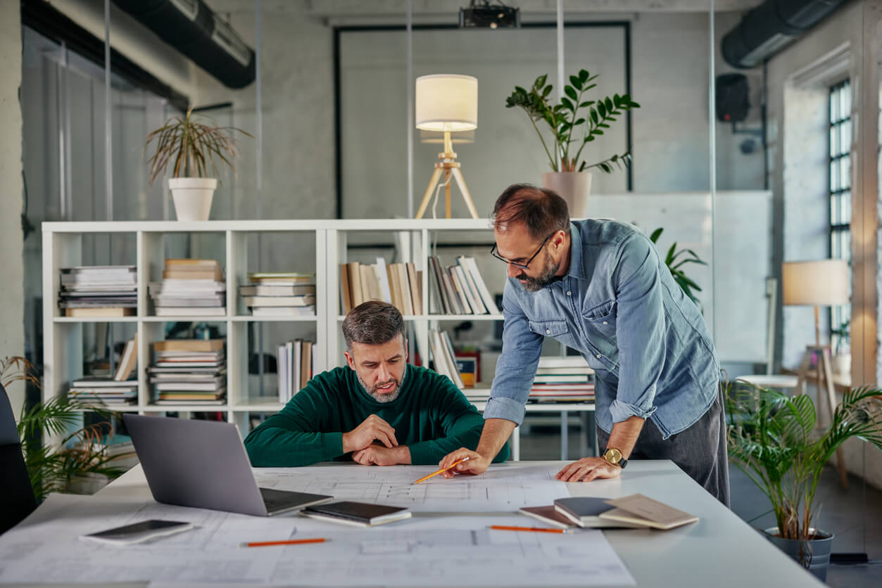 Les associés d'une SCI familiale examinent attentivement des plans immobiliers. Ils discutent de la possibilité d'acheter en SCI pour optimiser leur investissement, tout en bénéficiant d’une structure adaptée à la gestion et à la transmission du patrimoine familial.