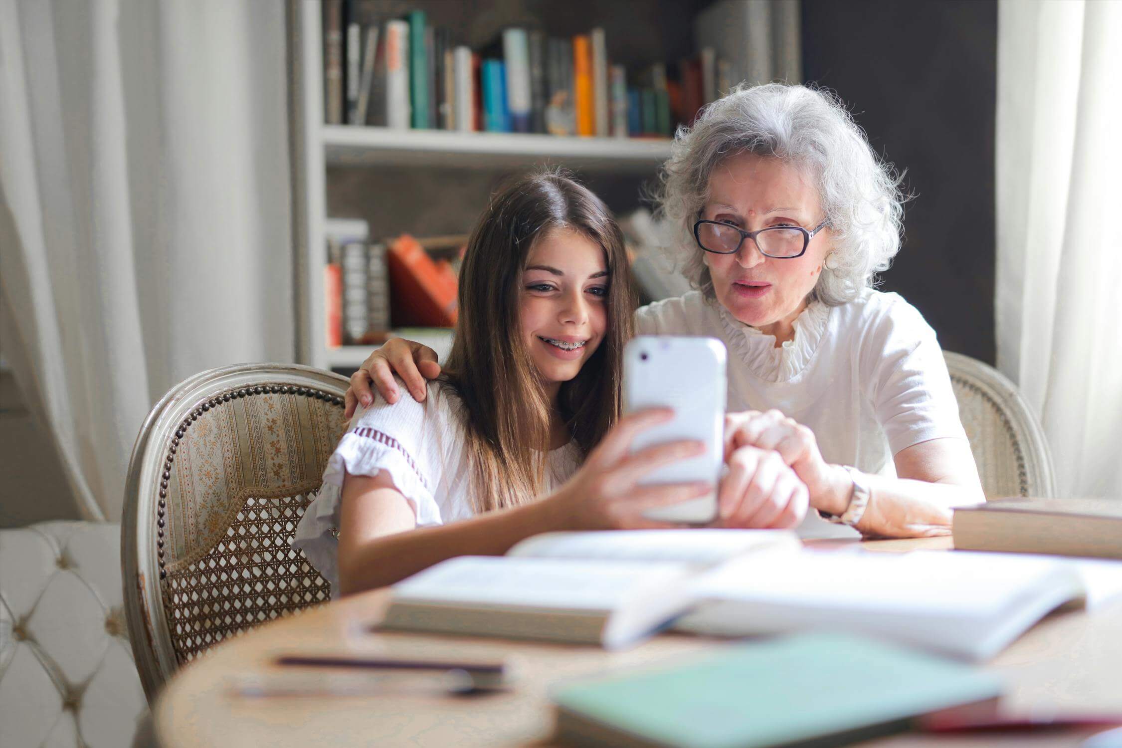 Image d'une grand-mère regardant un télepjone dans une bibliothèque d'un Lmnp Ehpad