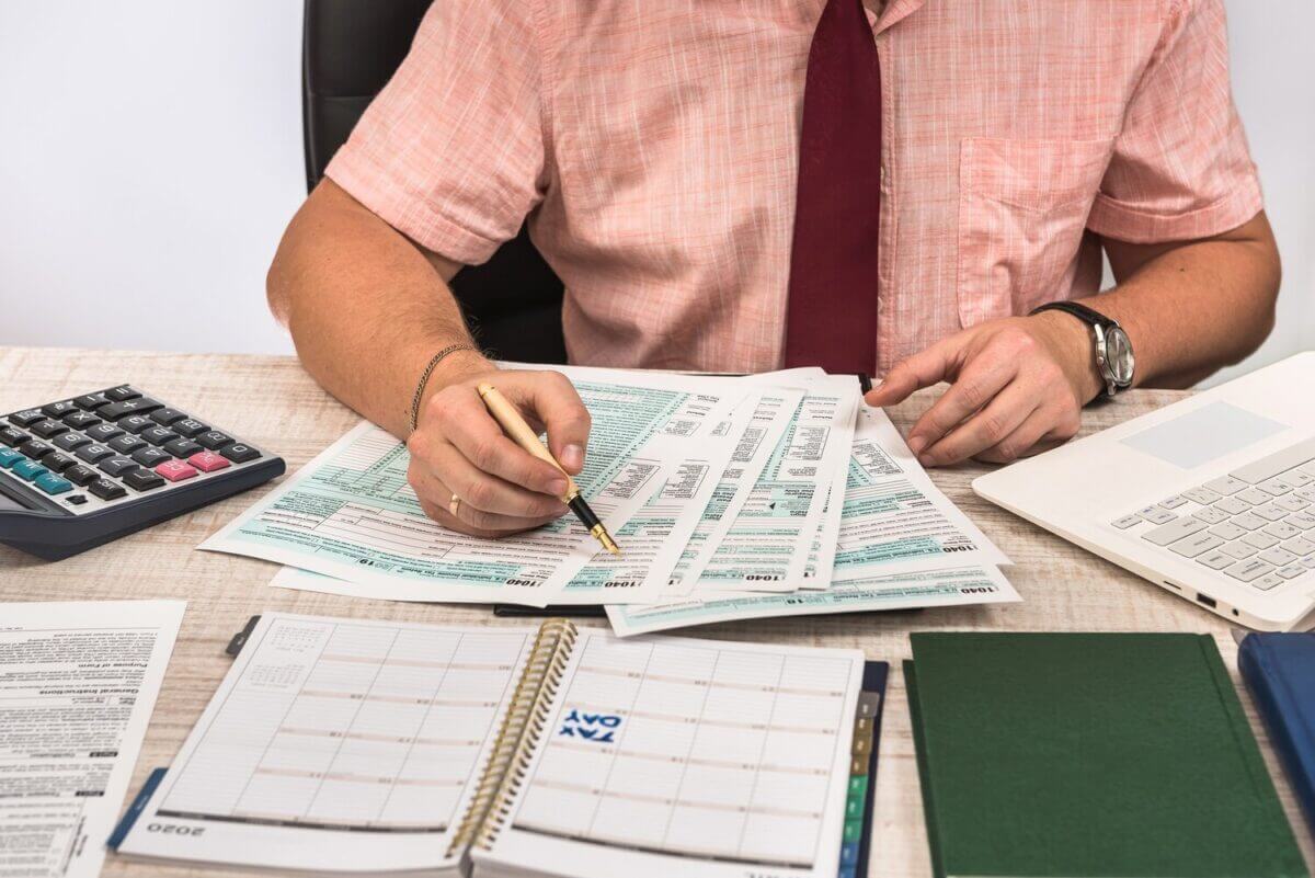 Un homme concentré examine des documents fiscaux pour optimiser sa déclaration de revenus locatifs sous le régime micro-foncier, recherchant simplicité et bénéfices de l'abattement forfaitaire de 30 %.